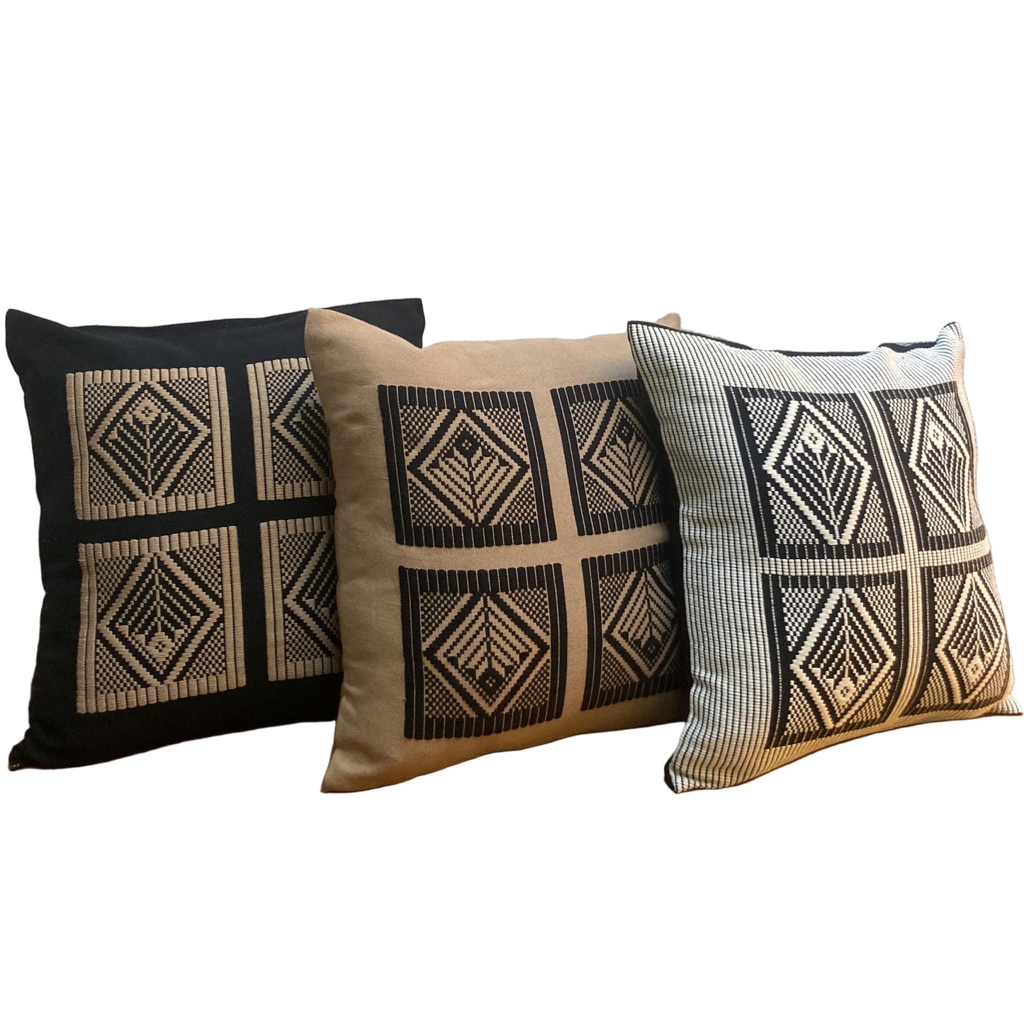 Three patterned pillows on a wooden surface with a textured wall background