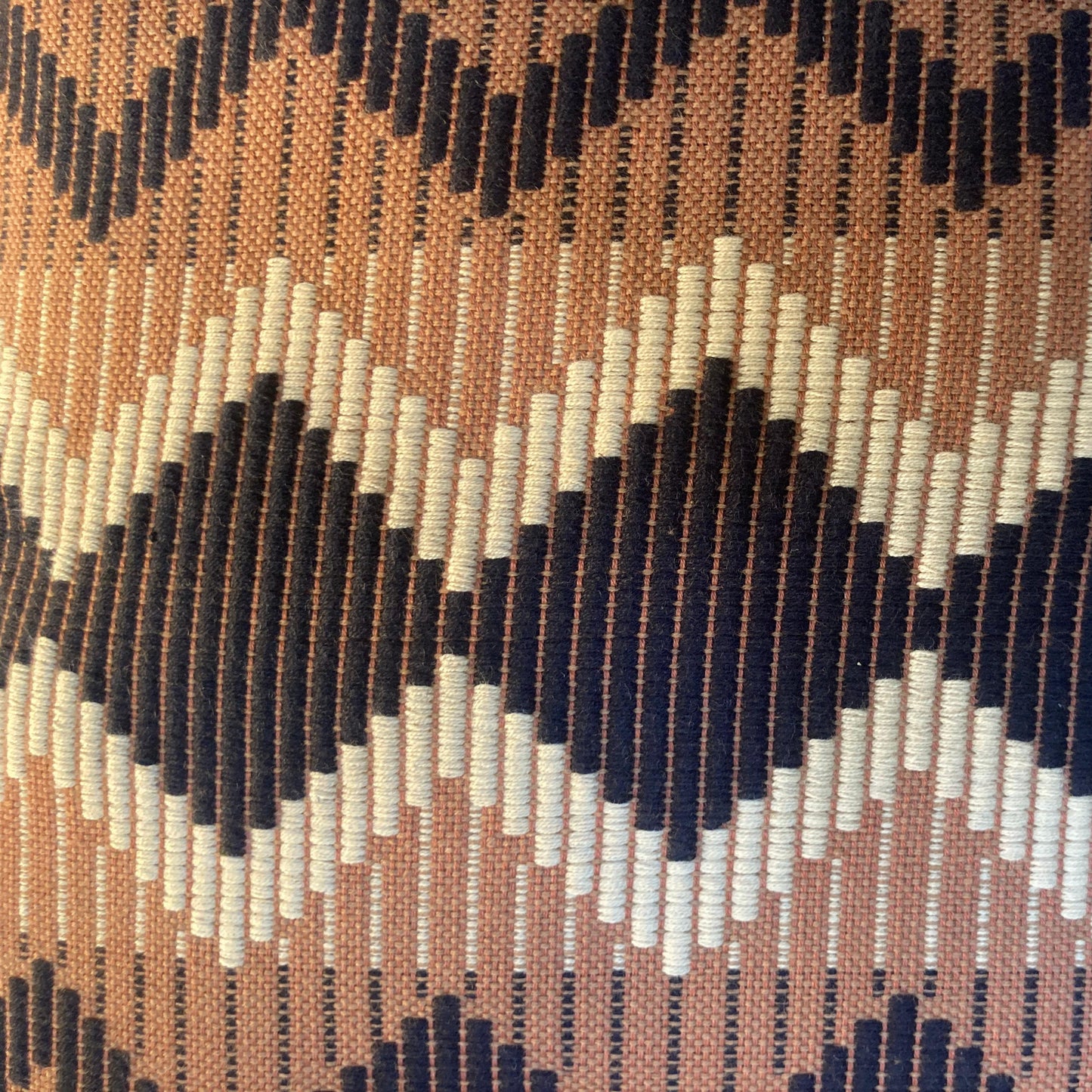 Close-up of a patterned fabric with zigzag design in brown, black, and white.