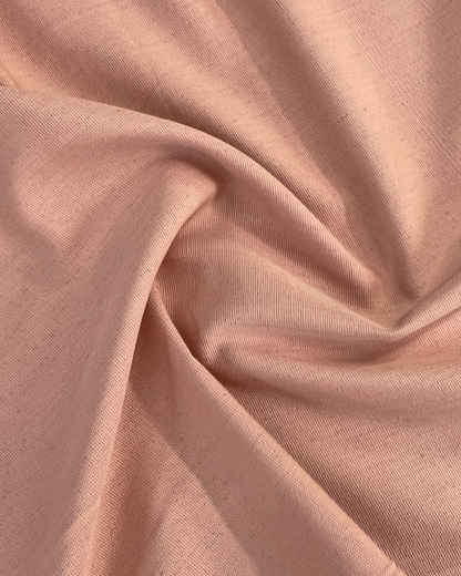 A close-up of draped dusty pink fabric with a fine textured weave, showing soft folds and shadows.